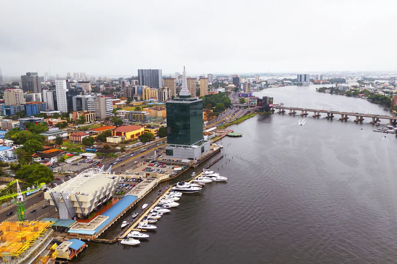 Aerial view of Victoria Island, Lagos: office towers, busy roads and car parks along the lagoon, with marinas and the Falomo Bridge.